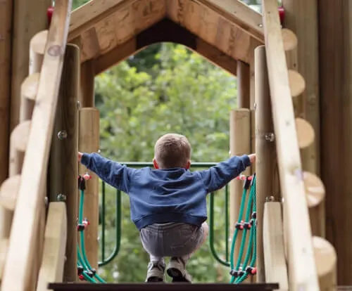 A child climbing a playground structure at a recreational facility.