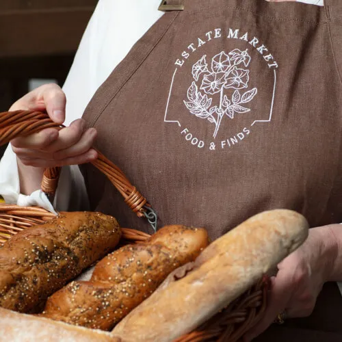 A person holding a basket of fresh bread at the Estate Market.