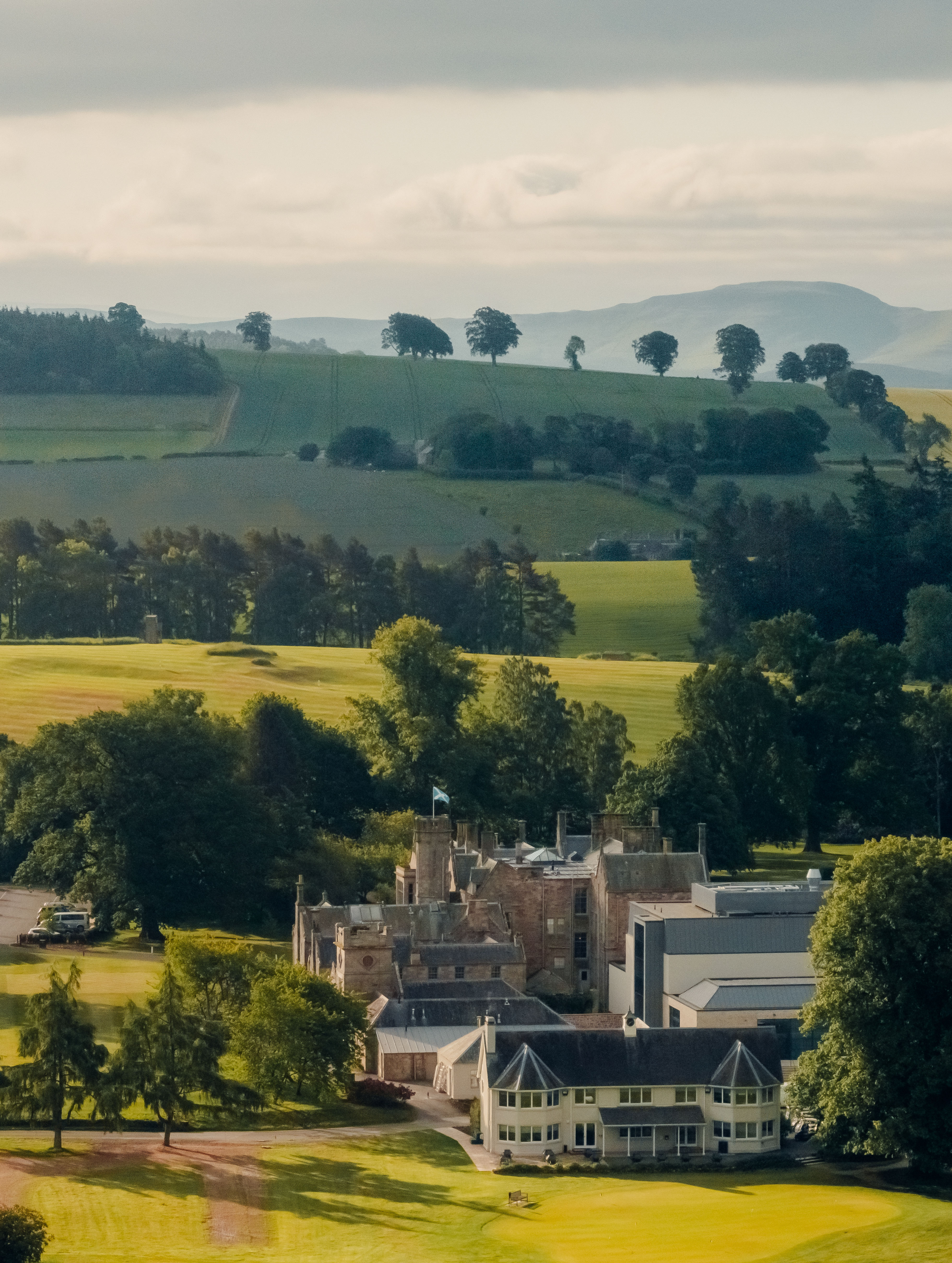 Historic castle in a scenic Scottish landscape with rolling hills and a golf course.