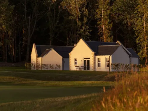 Charming buildings of Roxburghe Hotel surrounded by trees at sunset.