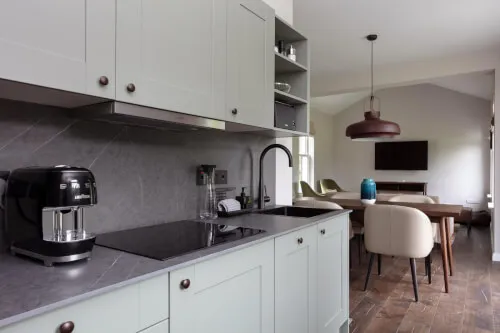 Modern kitchen with a coffee machine, sink, and stylish dining area.