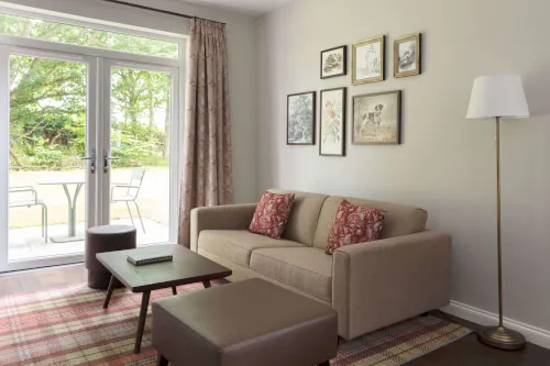 Cozy one bedroom cottage living room with sofa, lamp, and large windows at Roxburghe Hotel.